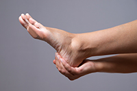 A woman holding her ankle in pain