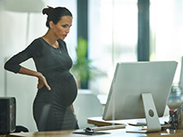 Pregnant Woman Standing At Desk